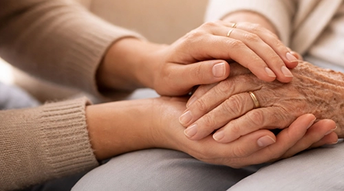 Younger hands holding an elderly person's hands